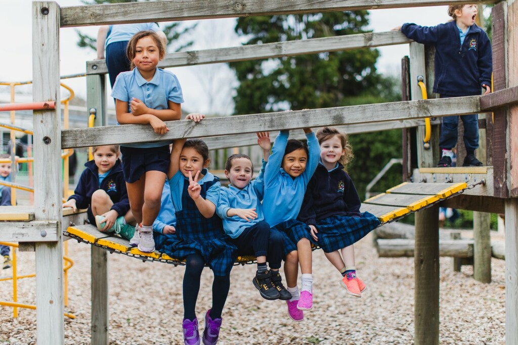 A number of school children in uniform on a playground bridge